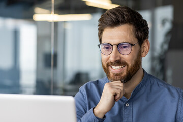 Happy businessman smiling while working on laptop