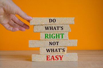 Do what is right not what is easy. Red words on the beautiful brick blocks on beautiful orange background. Businessman hand. Motivational quote.