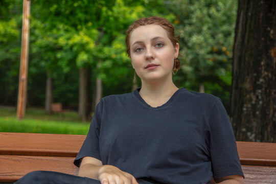 young woman thinking sitting on park bench outdoors student portrait