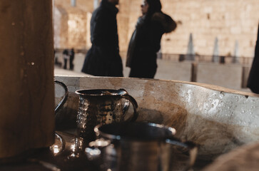 Cranes with water and a special ritual cups for washing hands near Western Wall, an important jewish religious site Jerusalem. Israel. Copper Pots for ritual Ablution in front of the Wailing Wall.