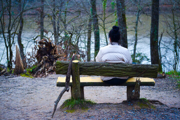 Solitude in Nature: Woman Sitting on Riverside Bank