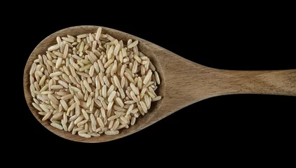 Gordijnen Brown long rice in wooden spoon, uncooked and hulled, isolated on black, top view  © dule964