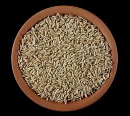 Poster Brown rice in clay pot, uncooked and hulled, isolated on black, top view  © dule964