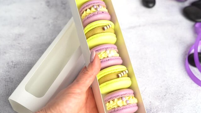 A woman's hand takes a yellow macaroon close-up.
