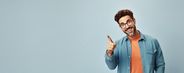 Smiling Handsome man giving thumbs up with copy space for text in blue coat on light blue background - obrazy, fototapety, plakaty