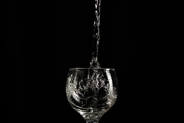 Stream of water in drops falling into a glass cup