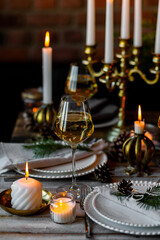Rustic Scandinavian style zero waste eco-friendly dinner table decor for Christmas or new year family celebration. Wooden table, natural elements like pine cones, fir tree branches, candles