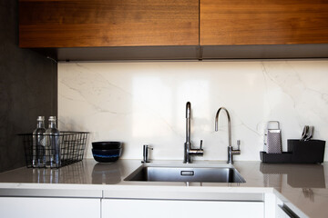 Kitchen brass utensils, chef accessories. Hanging modern kitchen with white marble wall and stone tabletop.