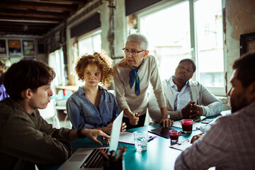 Team meeting with diverse group of professionals discussing project in a modern office