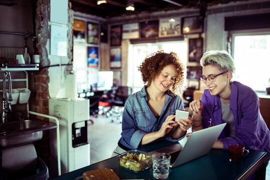 Young women using a smart phone while having a lunch break in a startup company office