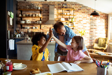 Father helping children with homework at kitchen table - obrazy, fototapety, plakaty