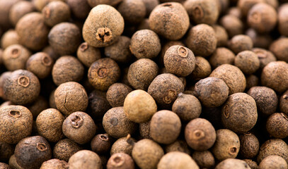 Pile of allspice, black peppercorn background. Jamaica pepper, allspice peppercorns or myrtle pepper backdrop, close up. Aromatic seasoning Pepper peas top view