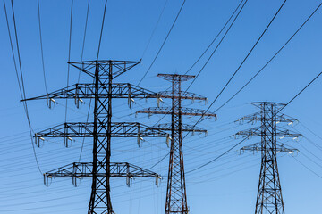 Several high voltage hydro electricity distribution towers on a blue sky