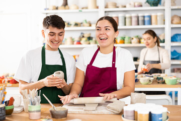 Young man and young woman making pottery from clay in workshop