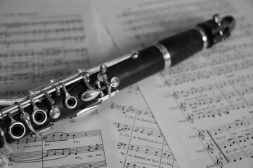 Detail of a clarinet on some music sheets. Black and white image