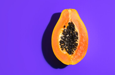 Papaya fruit on bright violet background. Half of fresh organic Papaya exotic fruit close up. Top view. Vegan food  - 779252771
