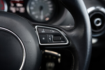 The steering wheel of a car has a lot of buttons and switches, including a gear shift and a brake...