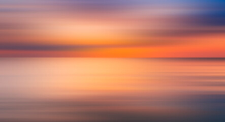 Naklejka na ściany i meble Abstract sun is setting over the ocean, casting warm glow on water. The sky is filled with clouds, creating a moody atmosphere. reflection of sun on water is a beautiful sight to behold, motion blur.