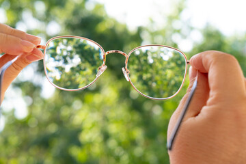 glasses with thin metal frame in female hands, individuals with poor vision adapt lifestyle choices...