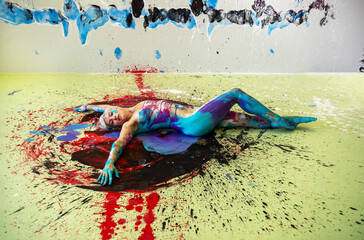 Young naked woman in turquoise and magenta paint color, painted, lies decorative, elegant on the colorful studio floor. Creative, abstract expressive bodypainting art