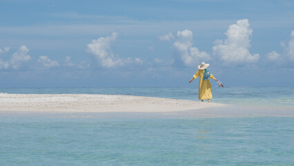 A woman in a yellow dress is having fun on a sand island