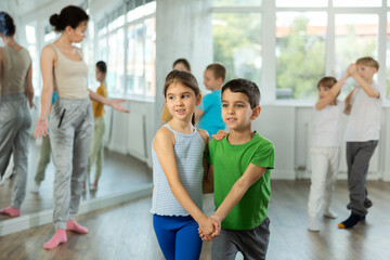 Preteen children learn to dance tango under guidance of a teacher in the ballroom