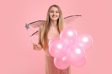 Beautiful girl in fairy costume with wings, magic wand and balloons on pink background