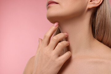 Fototapeta na wymiar Woman touching her neck on pink background, closeup