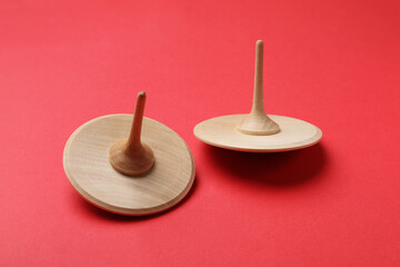 Two wooden spinning tops on red background