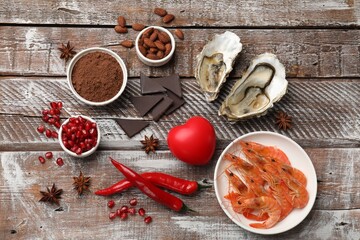 Natural aphrodisiac. Different food products and heart model on wooden table, flat lay
