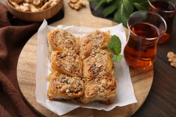 Eastern sweets. Pieces of tasty baklava and tea on wooden table, closeup