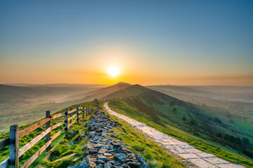 Stone footpath and wooden fence leading a long The Great Ridge in the English Peak District