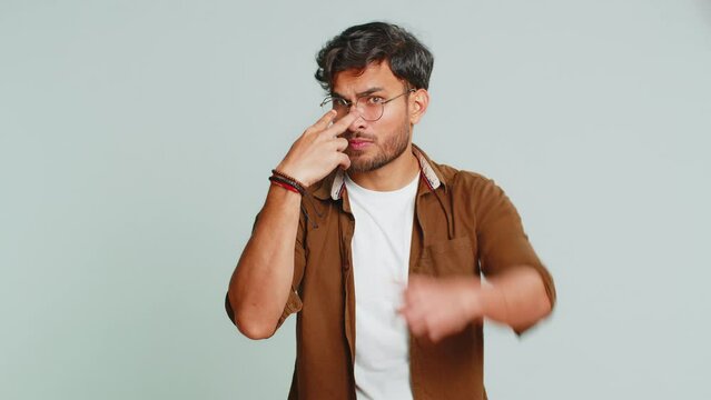 I am watching you. Confident attentive man pointing at her eyes and camera, show I am watching you gesture spying on someone. Handsome disappointed Indian guy isolated on gray studio background