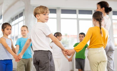 Obraz premium Group of boys and girls with teacher dancing traditional round dance in studio