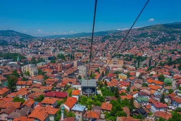 Foto auf Glas Trebevic gondola raising from the old town of Sarajevo, Bosnia and Herzegovina © dudlajzov