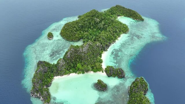Scenic islands, surrounded by coral reef, rise from Raja Ampat's tropical seascape. This part of Indonesia is known as the heart of the Coral Triangle due to the marine biodiversity found there.