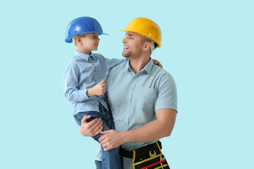 Happy father and his little son in hardhats with tools on blue background