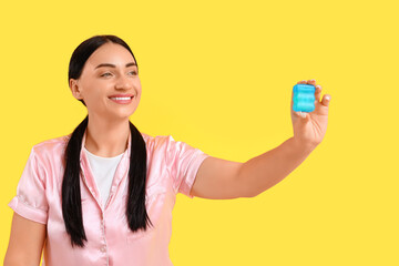 Beautiful young happy woman with dental floss on yellow background