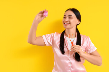 Beautiful young happy woman with dental floss and tongue scraper on yellow background