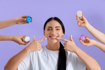 Beautiful young happy woman and hands with different dental floss on purple background