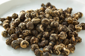 A closeup view of a pile of jasmine pearls loose leaf tea.