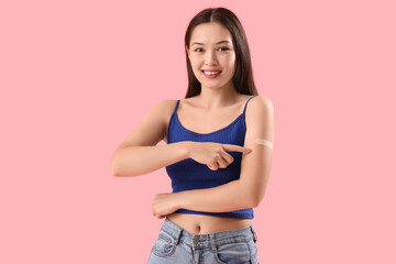 Young woman pointing at applied medical patch on her arm against color background - obrazy, fototapety, plakaty