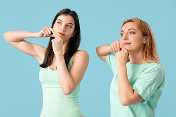 Beautiful women doing face building exercise together on blue background