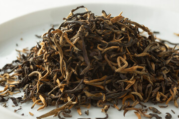 A closeup view of a pile of loose leaf golden yunnan black tea.