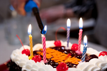 Lighting candles with lighter on a birthday cake close up