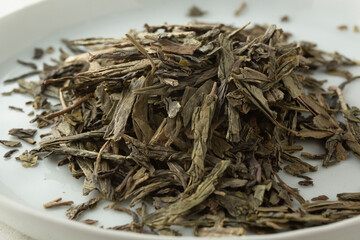 A closeup view of a pile of loose leaf lung ching green tea.