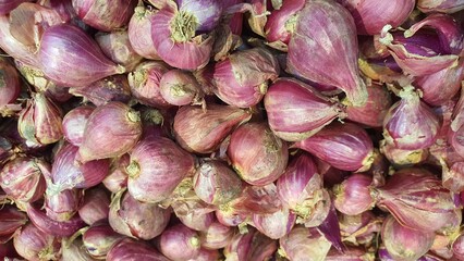 Close up pile of fresh red onions placed together in local market as a background.	
