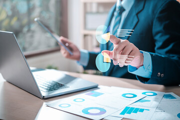 chart, discussion, document, strategy, graph, plan, management, marketing, financial, statistic. A man is working on a laptop. He is pointing at a screen with a pie chart and a bar chart.