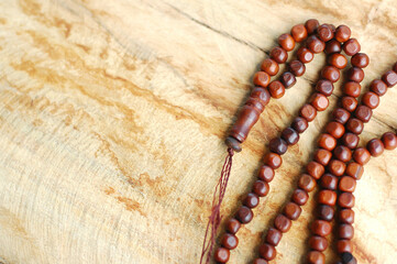 Muslim prayer rosary beads isolated on wooden background.