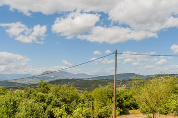 Rural landscape with power lines cutting across a green terrain with distant hills in Meteora, Greece
